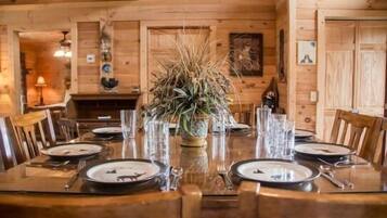 A wooden dining table set for four with a centerpiece of dried plants.