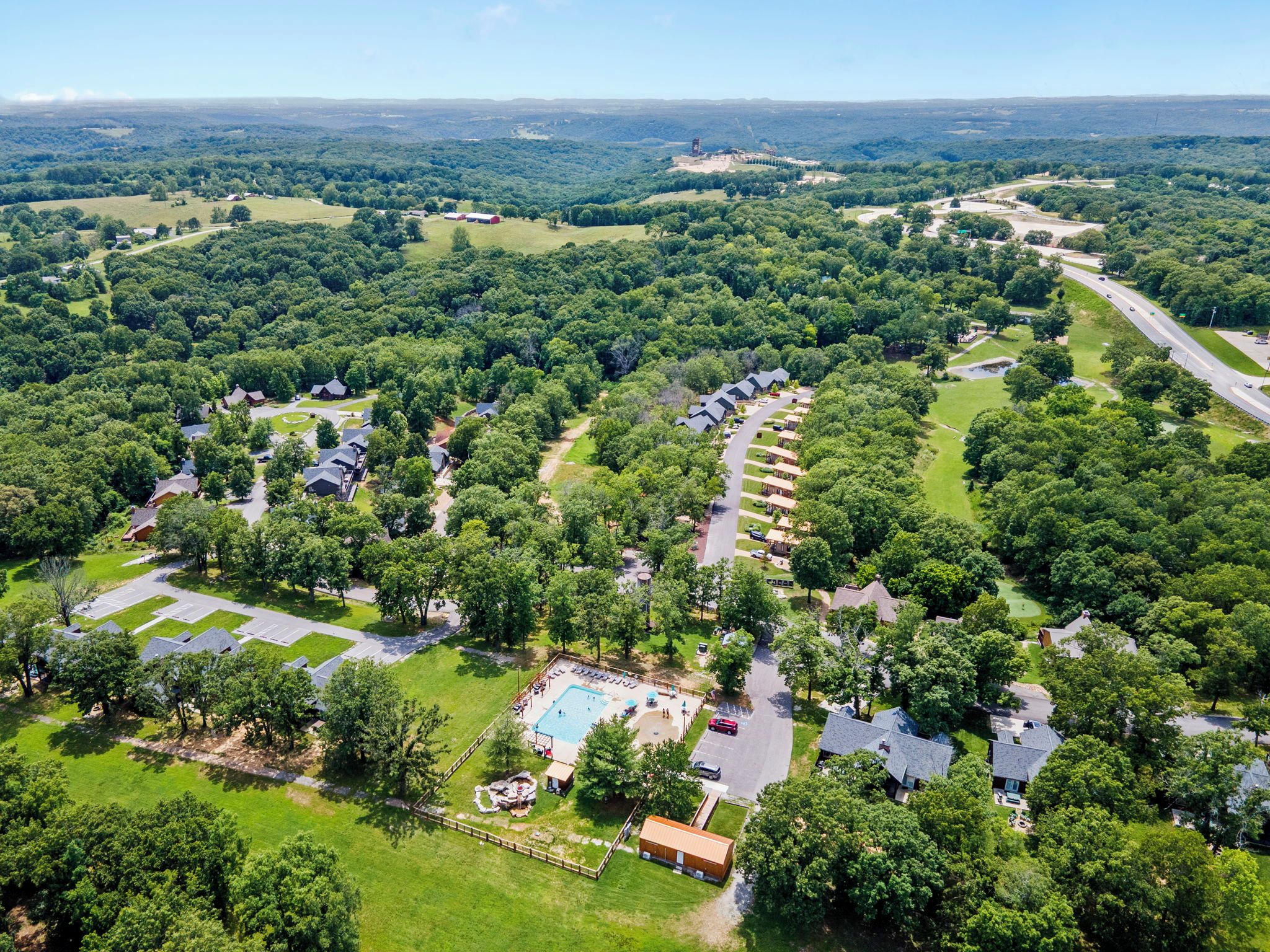 An aerial view of a residential area with houses, a swimming pool, and a road.