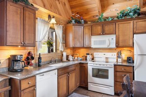 A kitchen with wooden cabinets, a microwave, a stove, and a coffee maker. - Traditional Log Cabin Near Big Cedar, PVT Fire Pit, Hot Tub, Scenic Woods, Trails End, Free Tickets! (Ridgedale)