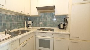 A kitchen with white cabinets, a double sink, a stove, and a coffee maker.