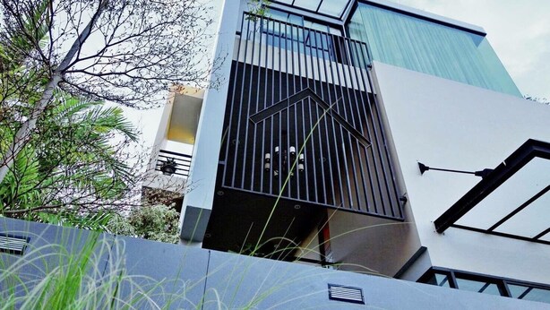 A modern building with a prominent black metal gate, a glass facade, and a white exterior wall.