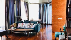 A modern living room with a wooden floor, a sofa, a coffee table, and a brick accent wall.