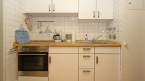 A kitchen with white cabinets, a double oven, a sink, and a wooden countertop. - Haus am Meer App. 71 (Sylt)