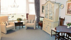 A living room with a sofa, armchairs, a dining table, and a cabinet. - App. Bölting 11 (Wenningstedt-Braderup)
