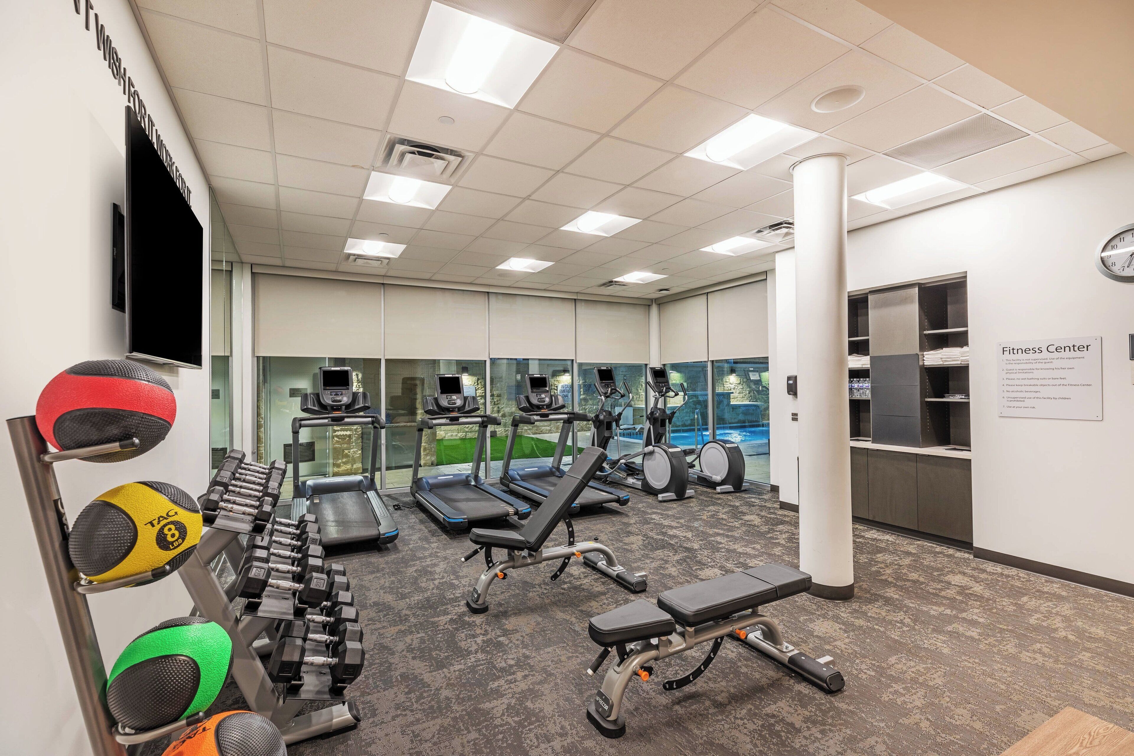 Ein Fitnessstudio mit Laufbändern, Crosstrainern und Gewichten.