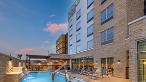 Un hotel con piscina, sillas de lounge al aire libre y fachada de piedra.