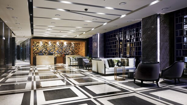 A modern lobby with a geometric floor pattern, a reception desk, seating area, and a decorative wall with shelves. - Traum Valley Hotel (Jeongseon)