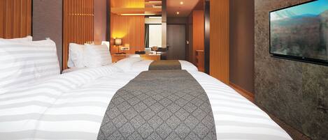 Een hotelkamer met een groot bed, een aan de muur bevestigde televisie en uitzicht op een bergachtig landschap.