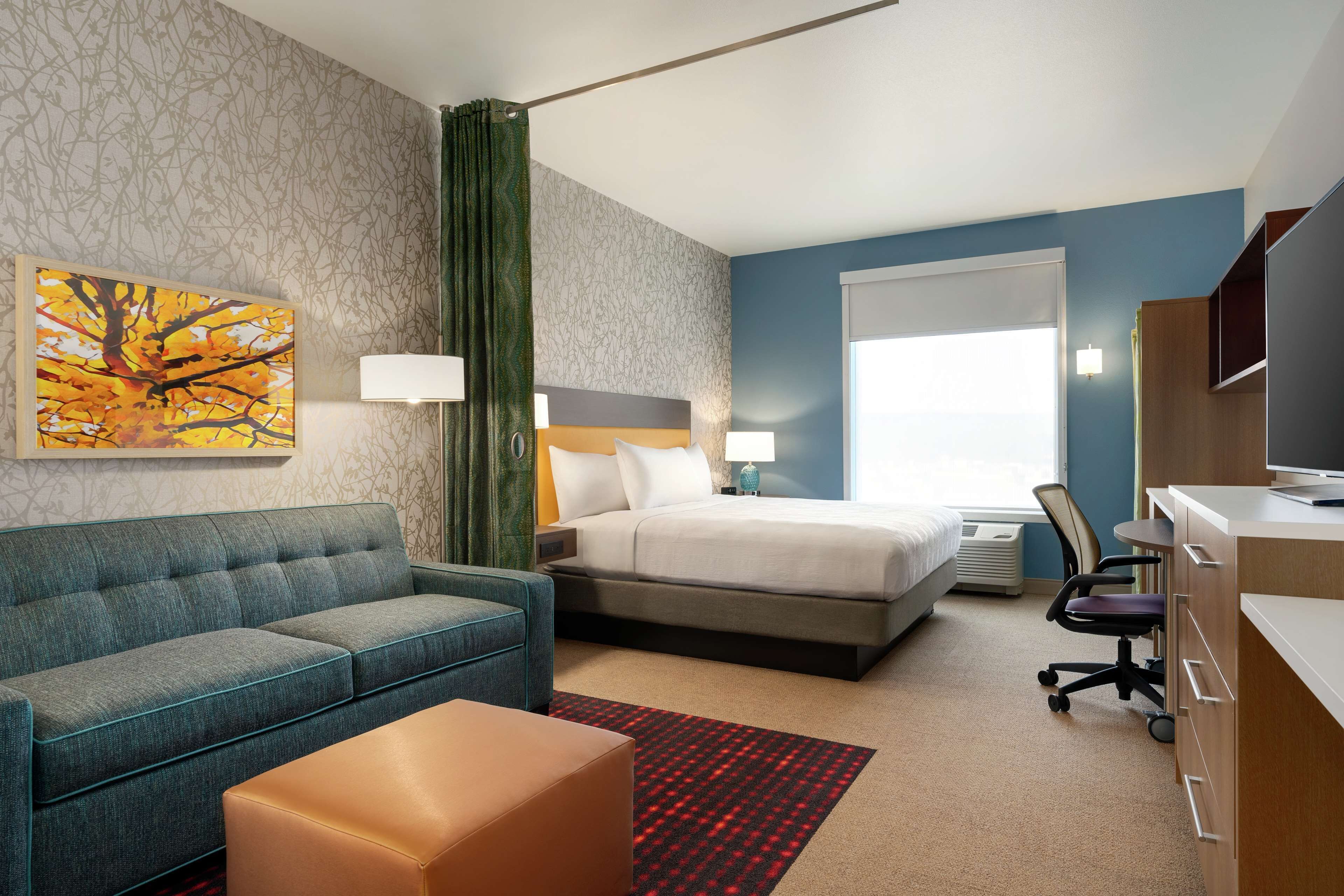 A hotel room with a bed, a sofa, a desk, and a TV.