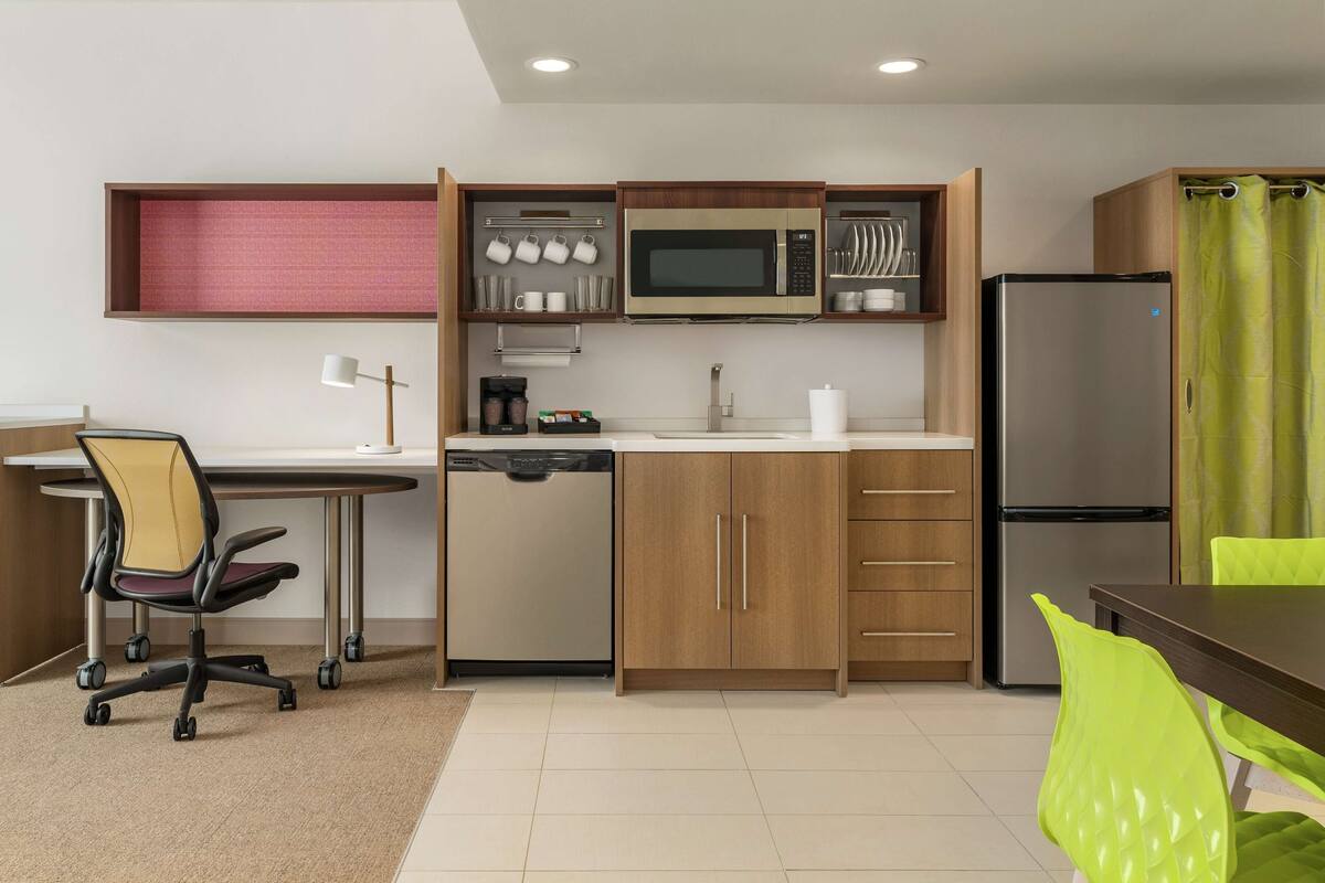 Eine kleine Küche mit Mikrowelle, Kühlschrank und Holzschränken.