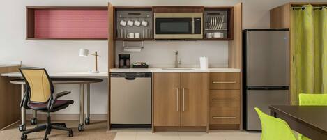 A compact kitchen with a microwave, refrigerator, and wooden cabinets.