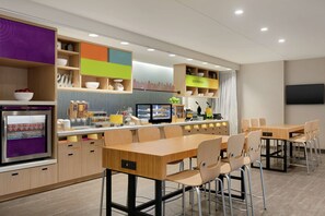 Una cocina moderna con una encimera larga, varias sillas y un televisor.
