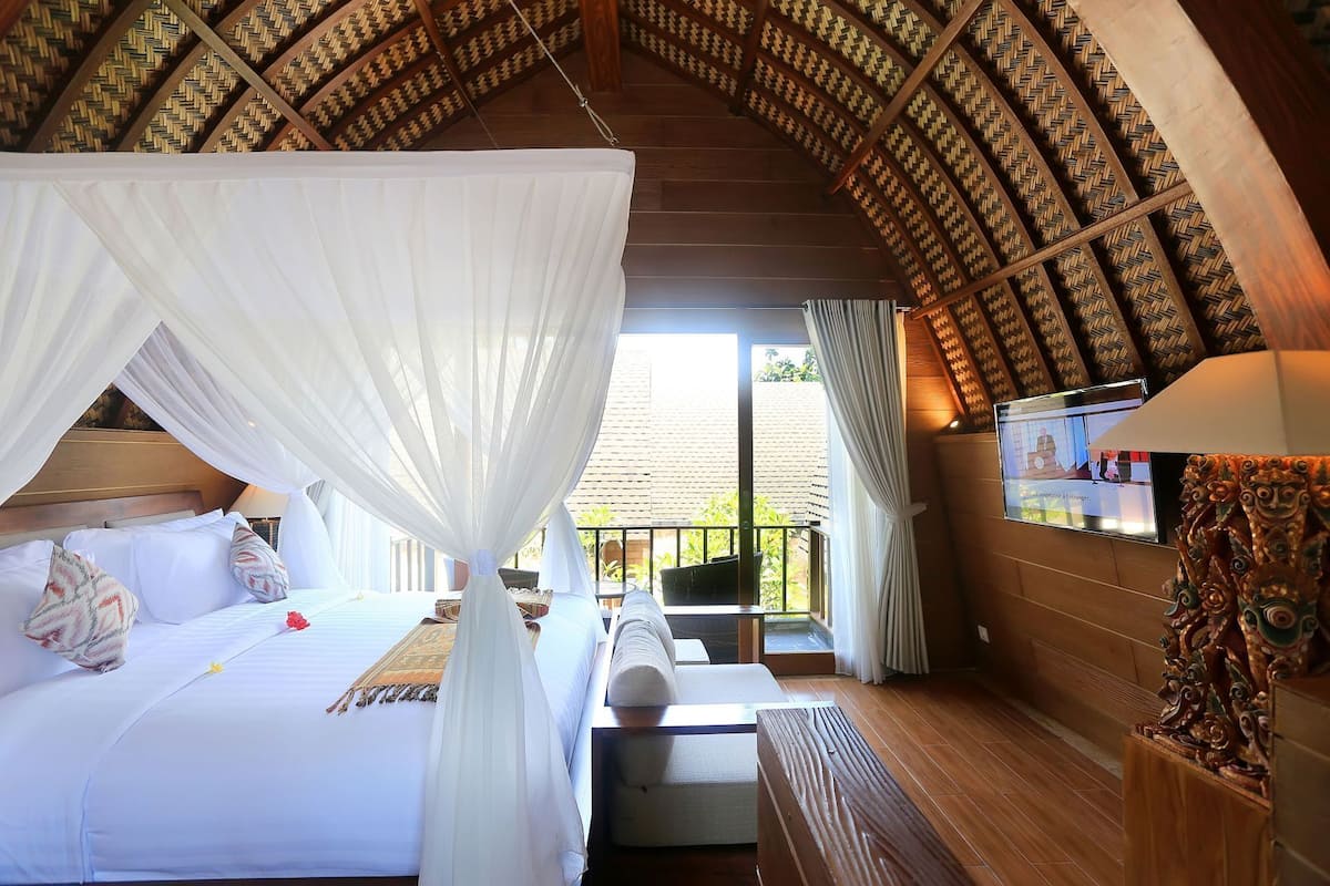 A room with a bed, a bench, a television, and a decorative wall.