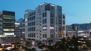 Um hotel com vários andares e sinalização indicando que está aberto 24 horas.