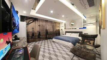 Habitación de hotel moderna con una cama grande, un escritorio con computadora, un televisor de pantalla plana y un espejo montado en la pared.