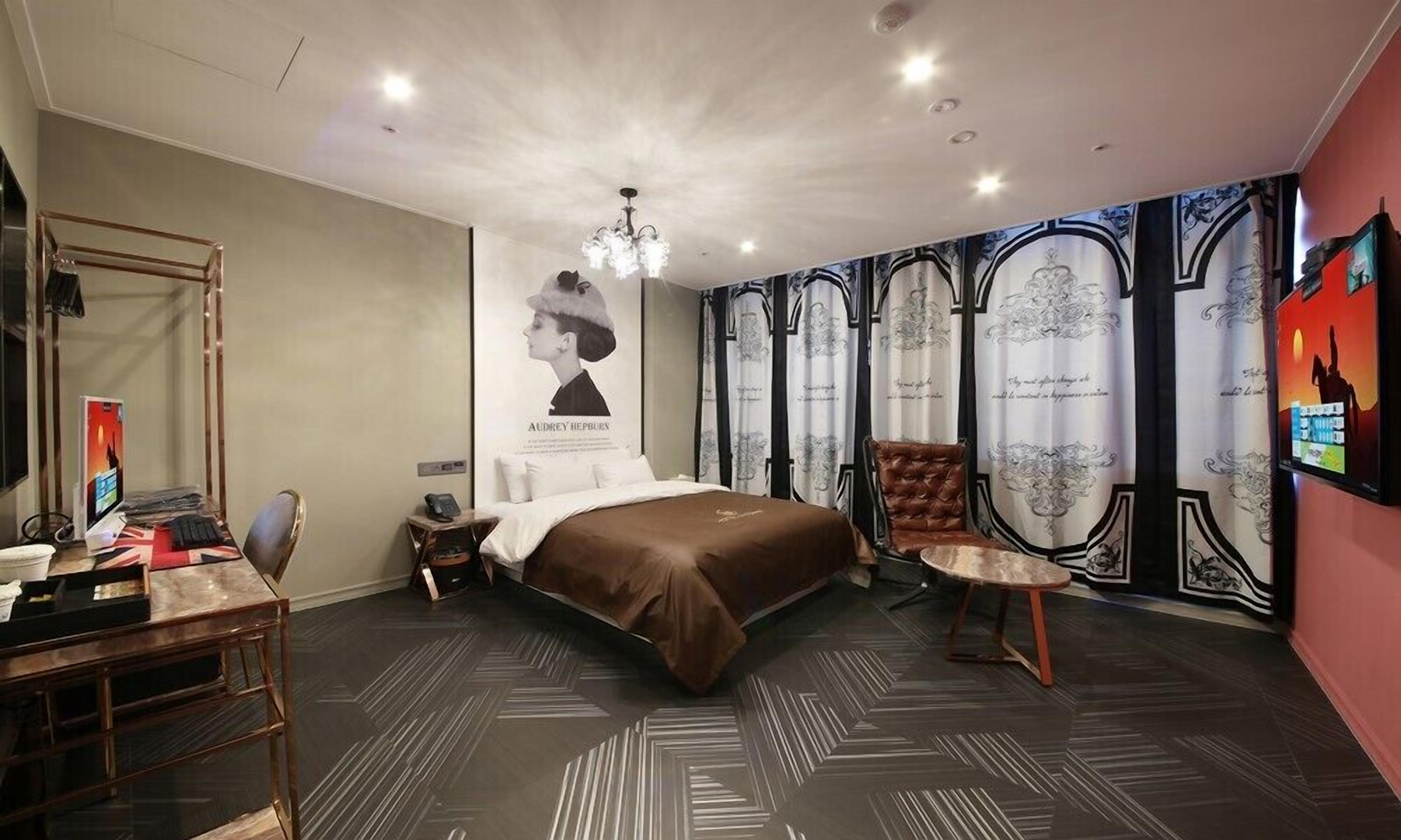 Ein modernes Schlafzimmer mit einem großen Bett, einem Schreibtisch mit Computer und einem Sessel.