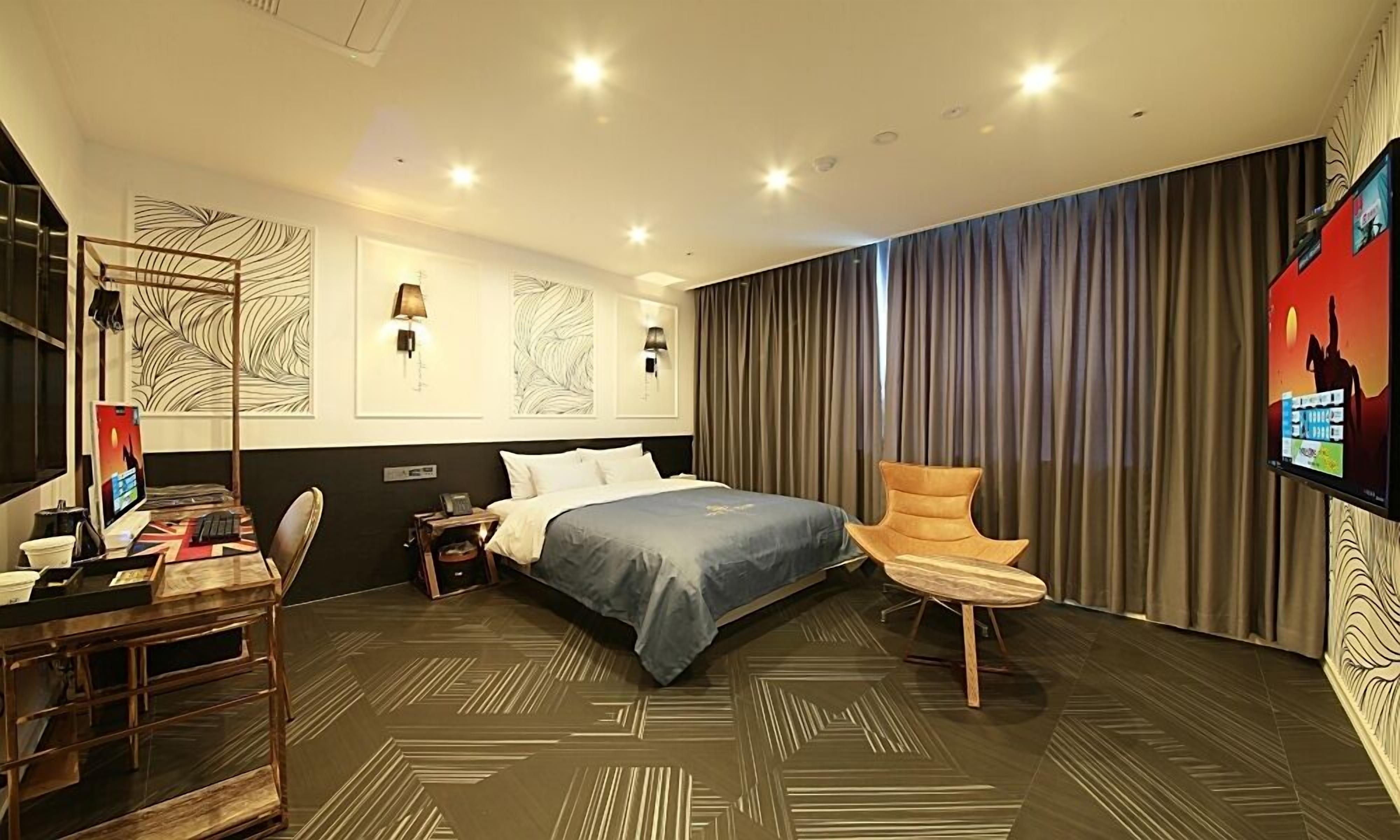 Una habitación de hotel con una cama, un escritorio con computadora, una silla y un televisor.