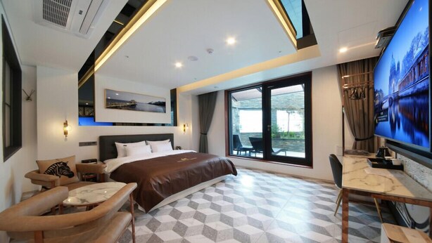 Quarto de hotel moderno com uma cama grande, uma escrivaninha e uma televisão.