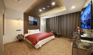 A hotel room with a bed, a TV, a desk with a computer, and a wall-mounted TV. - Gimpo Hotel M Tower (Gimpo)