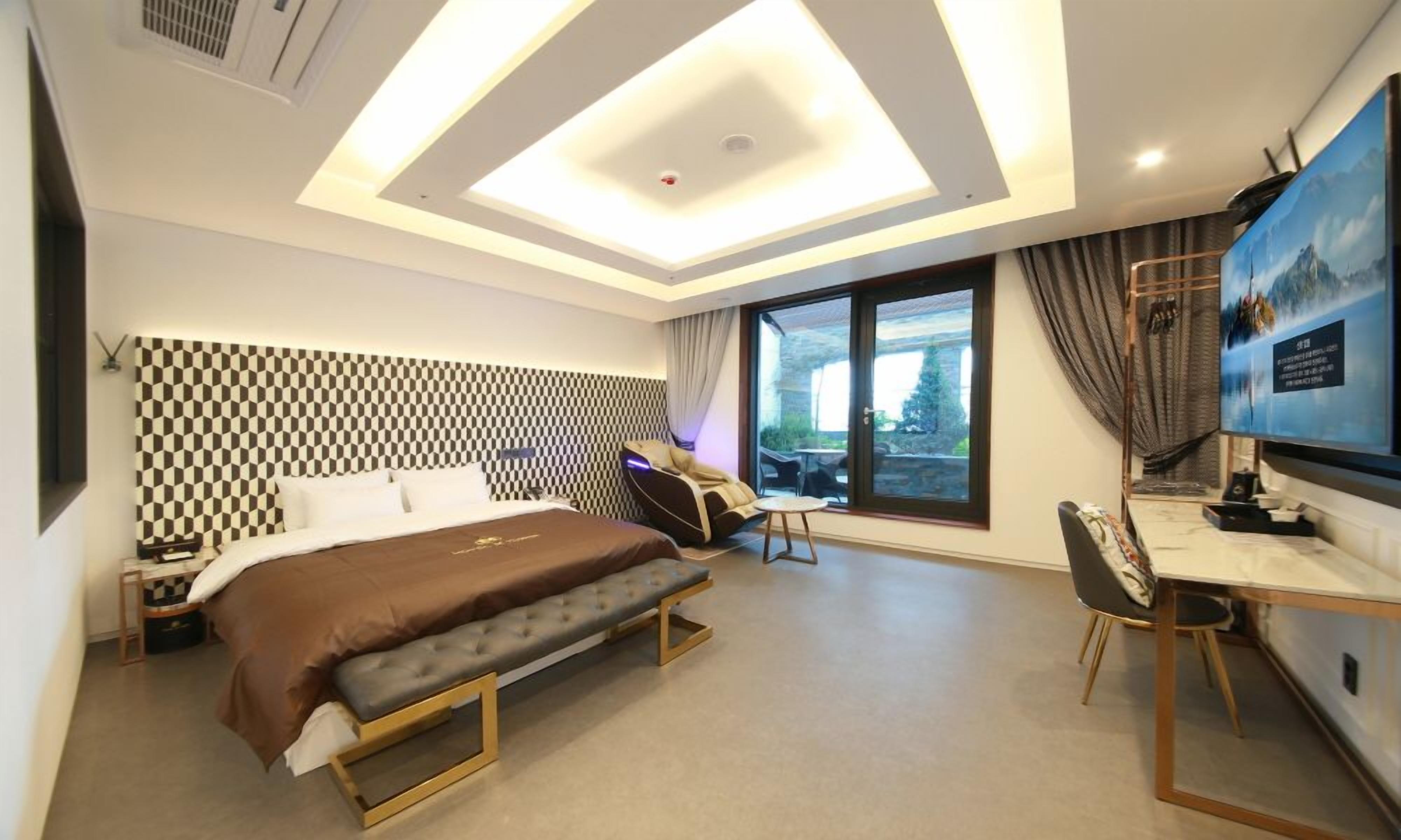 Moderni hotellihuone, jossa on sänky, työpöytä ja suuri ikkuna.