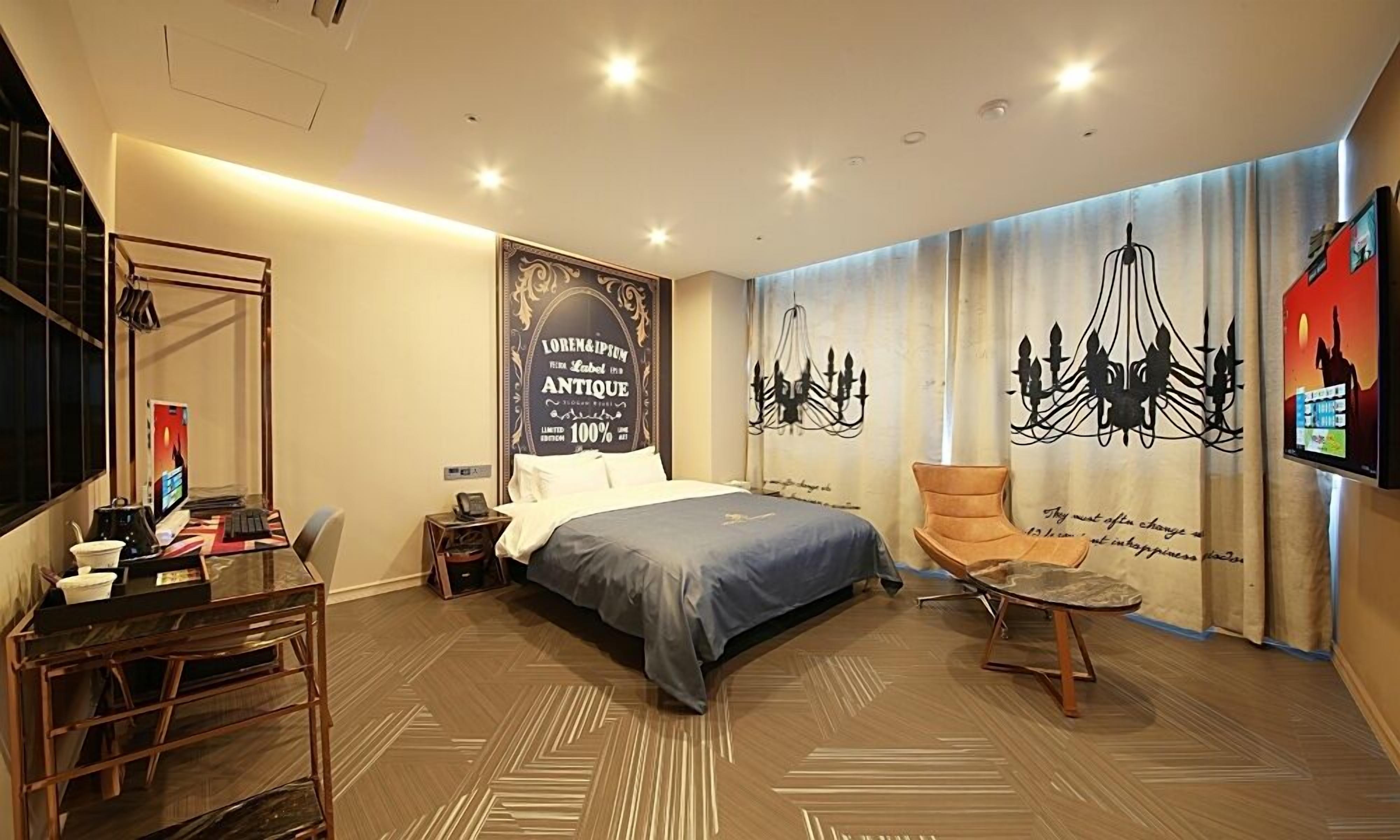 A hotel room with a bed, a desk, a chair, and a TV.