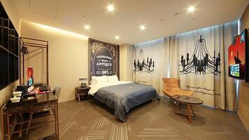 A hotel room with a bed, a desk, a chair, and a TV.