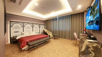 A hotel room with a bed, a desk, a chair, a TV, and a ceiling light.