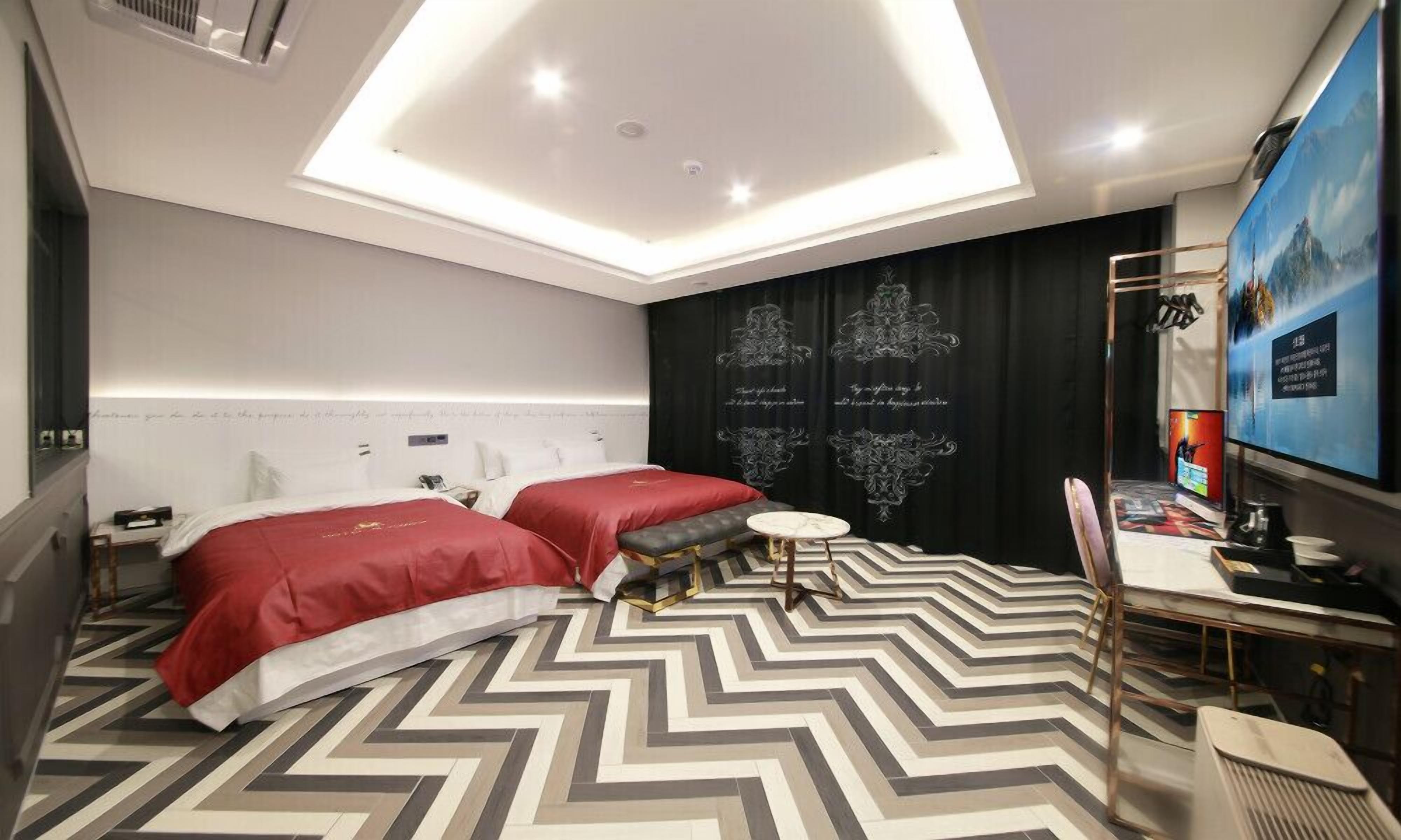 A modern hotel room with a large bed, a small round table, and a TV.