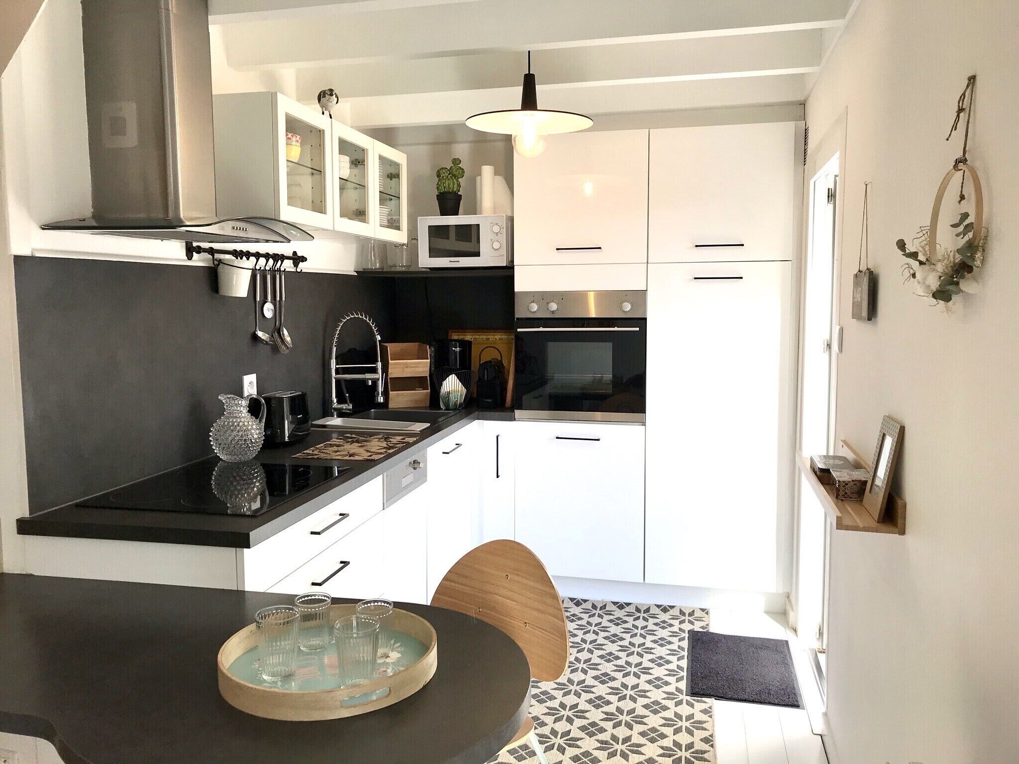 Een moderne keuken met witte kastjes, een zwart aanrecht en een houten eettafel.