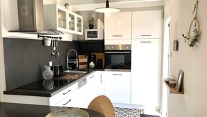 Een moderne keuken met witte kastjes, een zwart aanrecht en een houten eettafel.