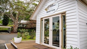 A reception area with a sign for McMillans of Metung Resort, a wooden deck, and a large potted plant. - McMillans of Metung Coastal Resort (Metung)
