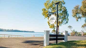 A McMillans Resort sign with a view of the water and a paved pathway leading to the entrance.
