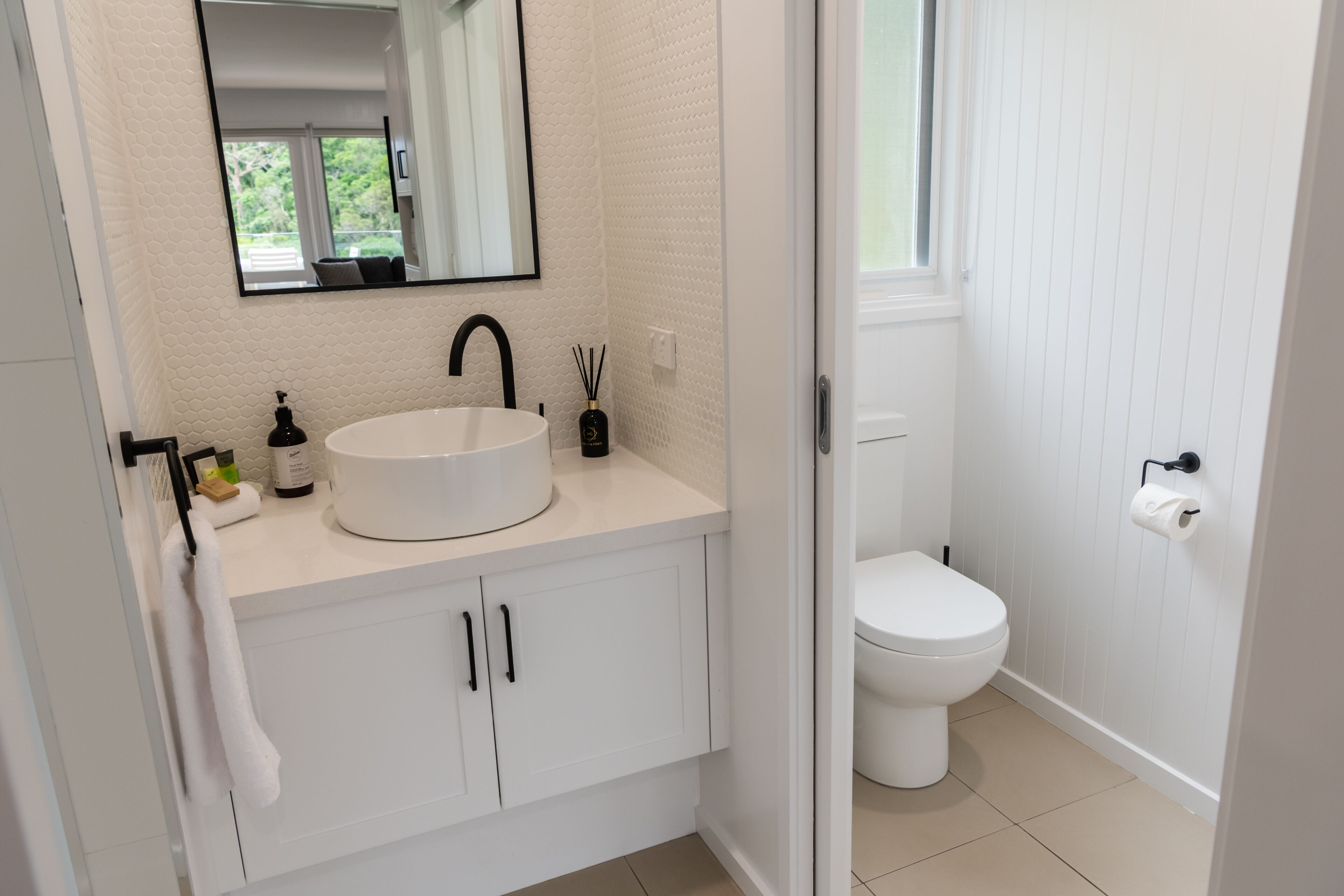 Ein Badezimmer mit einem weißen Waschbecken, einem schwarzen Wasserhahn und einer Toilette.