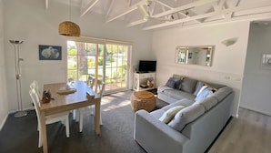 A spacious living area with a dining table, a sofa, and a television. - McMillans of Metung Coastal Resort (Metung)