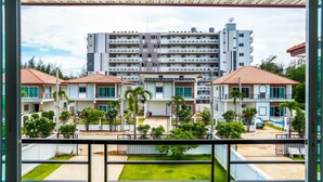 Um edifício residencial com vários andares, varandas, piscina e um jardim bem cuidado.