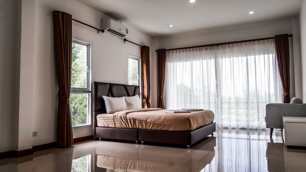 Quarto moderno com cama grande, mesa de cabeceira e janela com cortinas.