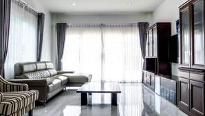 Uma sala de estar moderna com um sofá, uma poltrona listrada, uma mesa de centro e uma televisão.