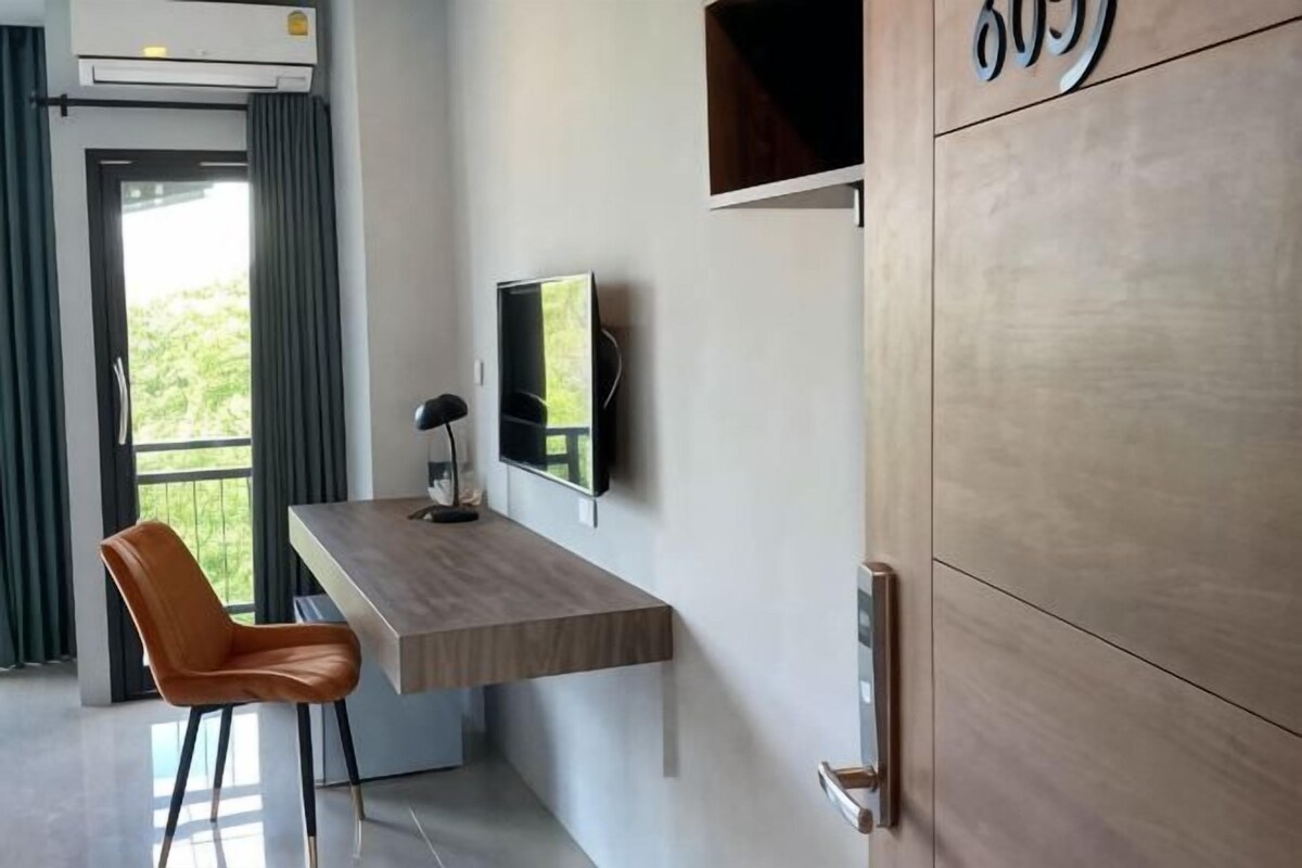 Quarto com escrivaninha, cadeira, televisão e armário.