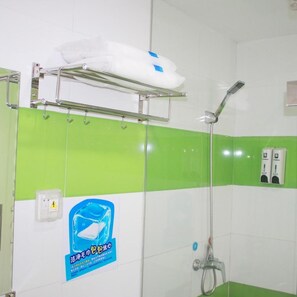 A bathroom with a shower, a towel rack, a soap dispenser, and a sign on the wall.
