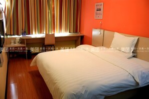 Habitación de hotel con cama, escritorio y silla. Se aprecia una ventana con cortinas a rayas.
