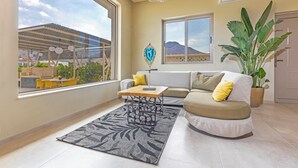 A living room with a sofa, a coffee table, a large window, and a plant.