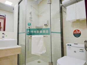 Kylpyhuoneessa on lasiseinäinen suihkukaappi, pesuallas ja wc. Suihkukaapin oven kahvassa roikkuu pyyhe.