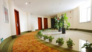 A hotel lobby with a curved carpet, potted plants, and wooden doors. - Greentree Inn Chaoyang City Chaoyang Street Fangzhi Road Express Hotel (Chaoyang)