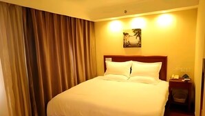 A hotel room with a large bed, a nightstand, a lamp, and a painting on the wall. - Greentree Inn Chaoyang City Chaoyang Street Fangzhi Road Express Hotel (Chaoyang)