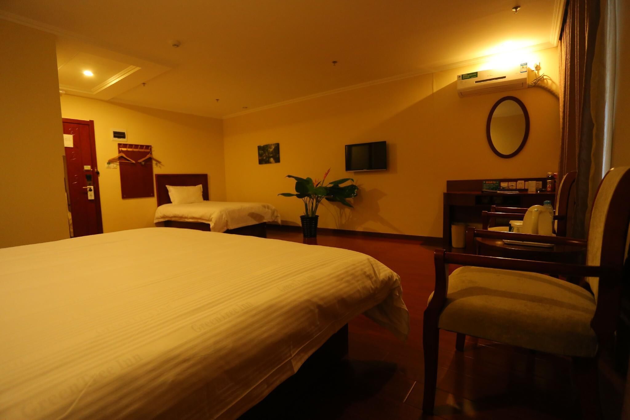 Habitación de hotel con dos camas, un escritorio, una silla, un televisor y una planta en maceta.