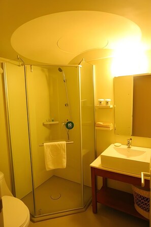 A bathroom with a glass-enclosed shower, a sink, and a toilet.