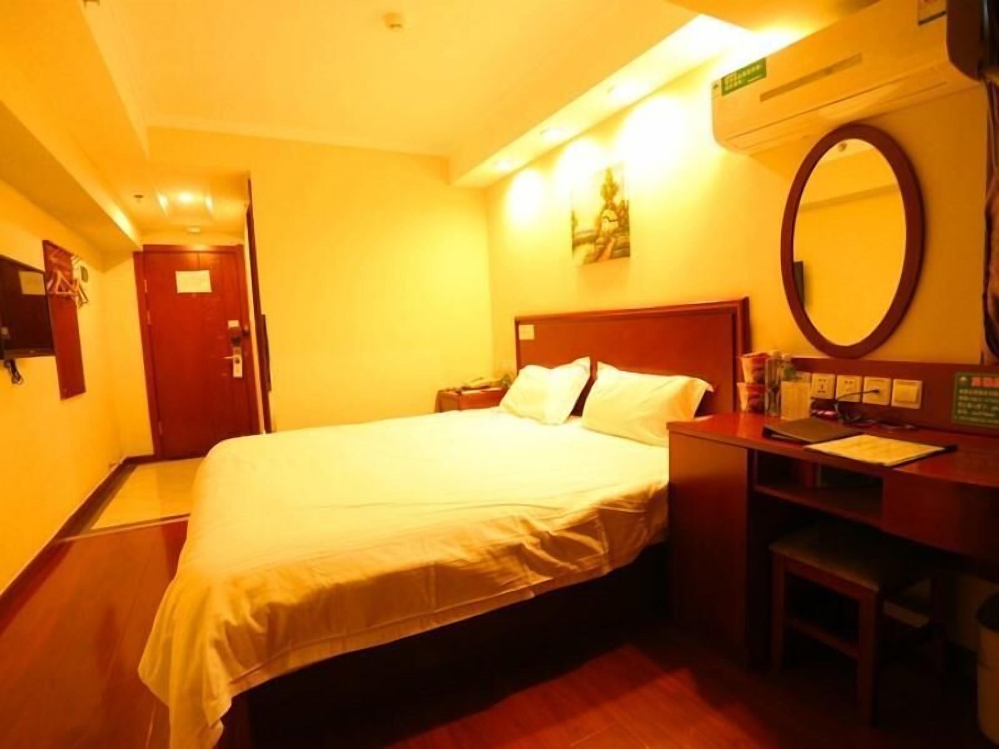 Ein Hotelzimmer mit Bett, Schreibtisch, Stuhl, Spiegel und Tür.