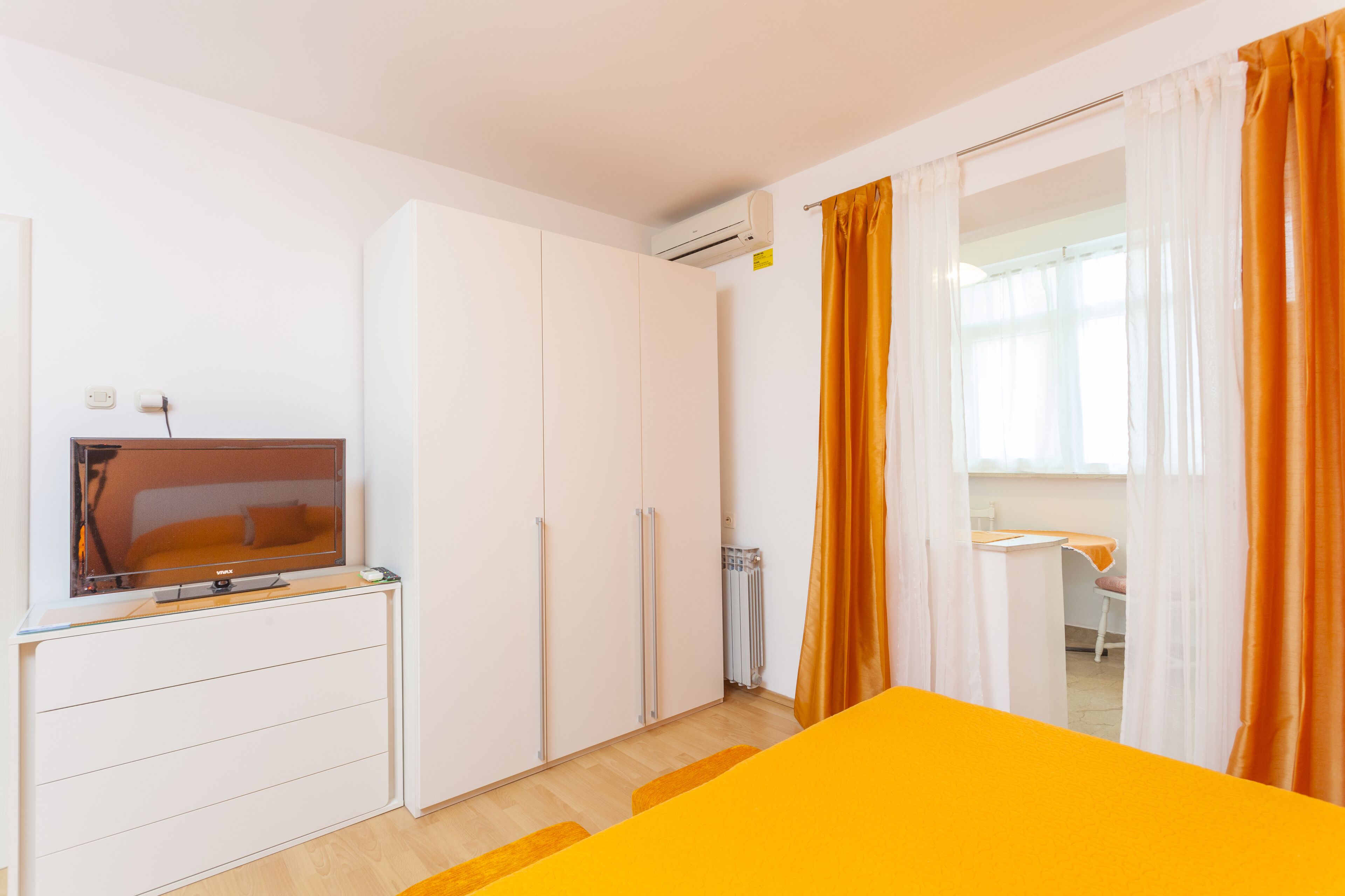 Una habitación con cama, televisión, armario y escritorio con silla.