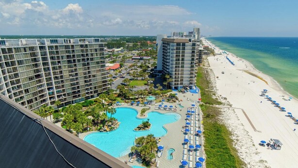A hotel with multiple high-rise buildings, a beachfront, and a pool area with sun loungers. - SanDBeach Villa, Edgewater Villa 3302-1st Floor-2 Patios-2 Bd/2Ba-Free Sandy Beach Tram! (Panama City Beach)
