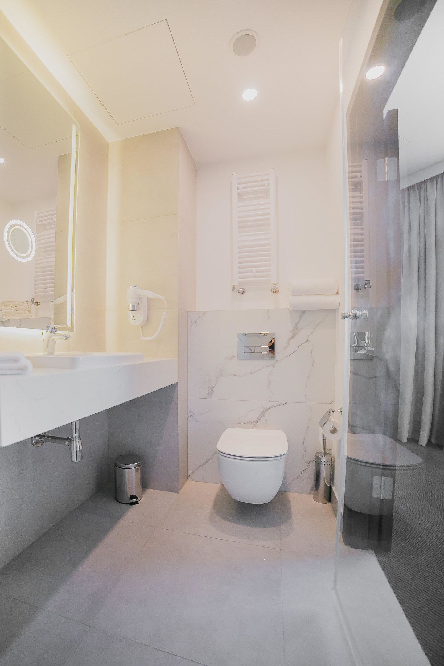 A modern bathroom with a white sink, mirror, and toilet.
